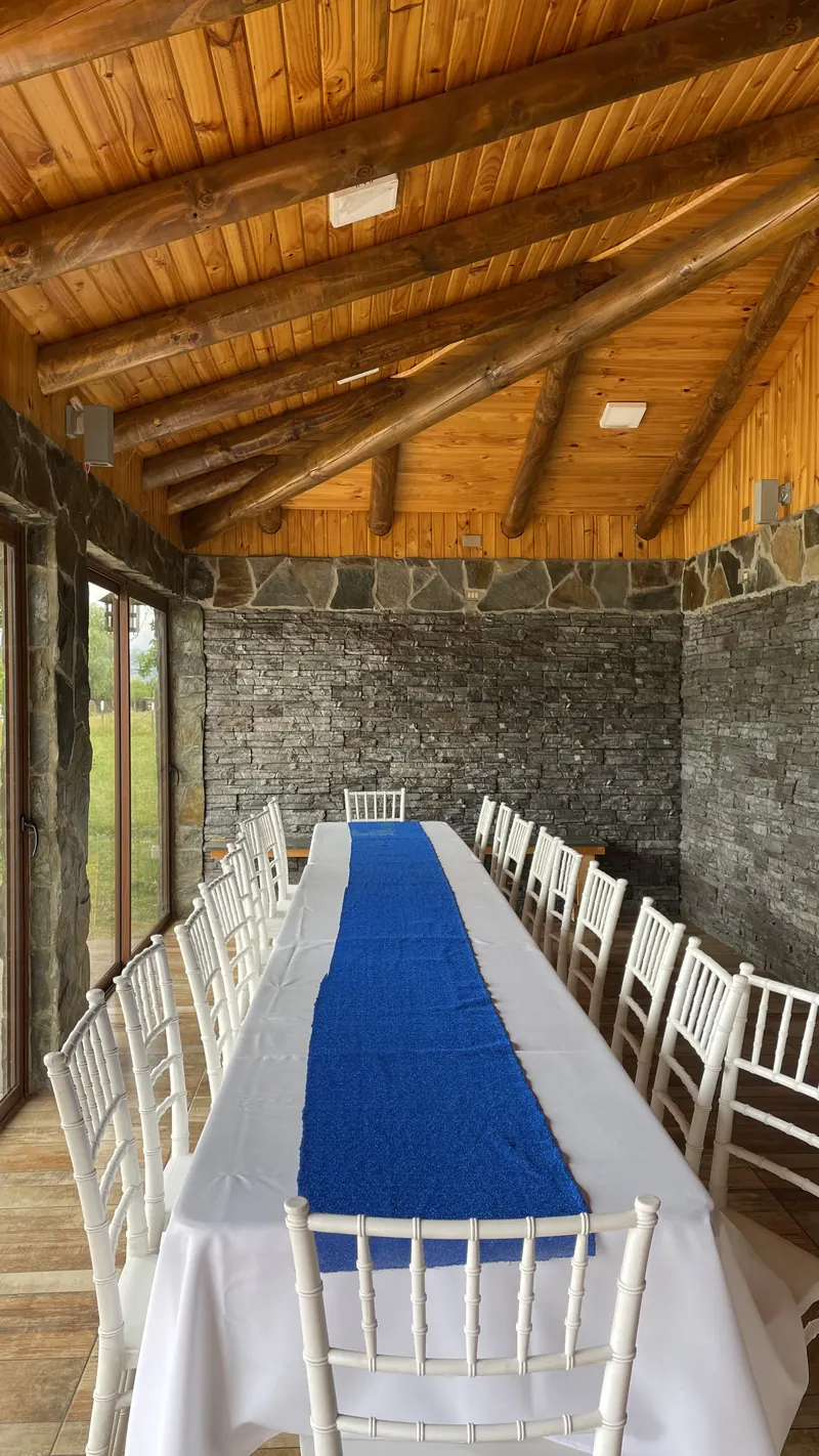 Mesa larga vestida de blanco con camino azul dentro del quincho