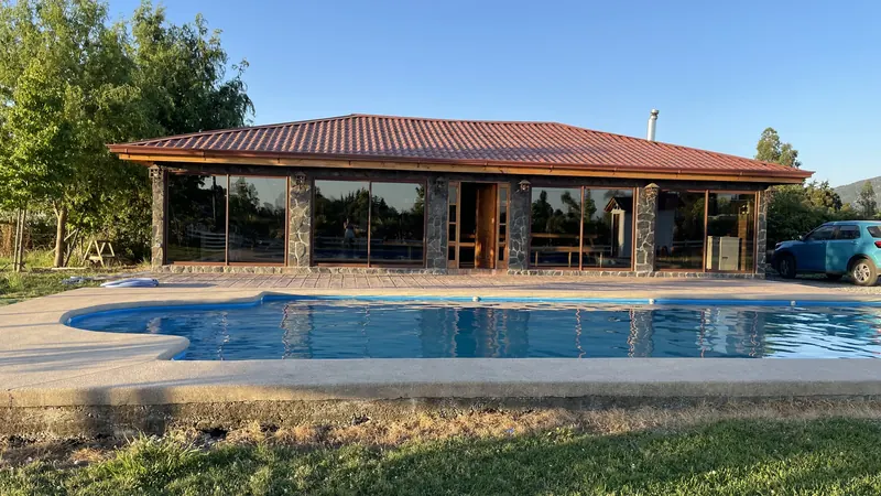 Vista del quincho con su piscina y jardín en una tarde soleada