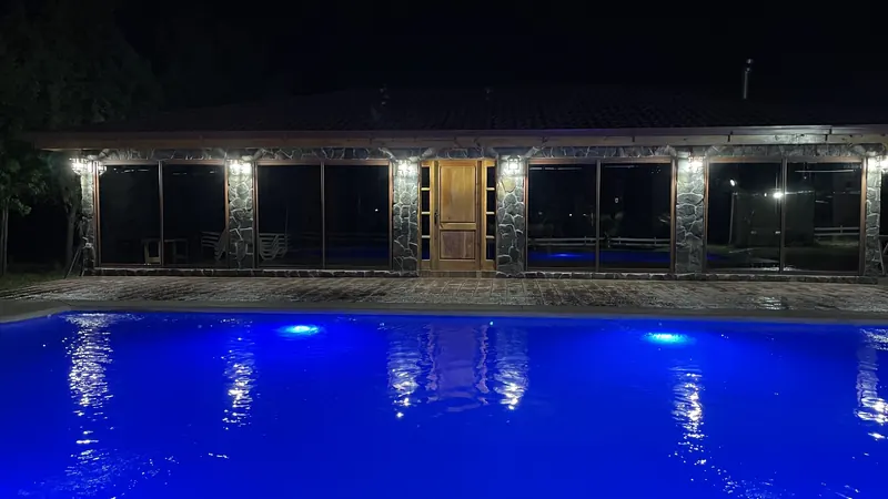 El quincho y la piscina iluminados de noche